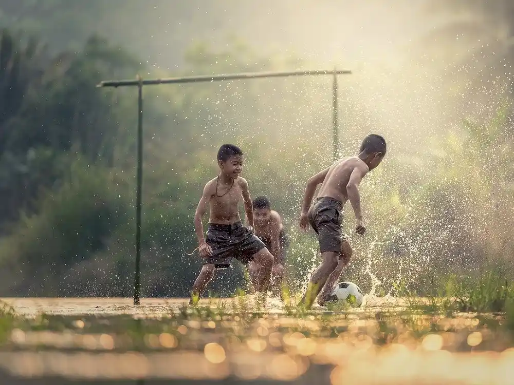 Children playing football outdoors in Brazil on a sunny day.