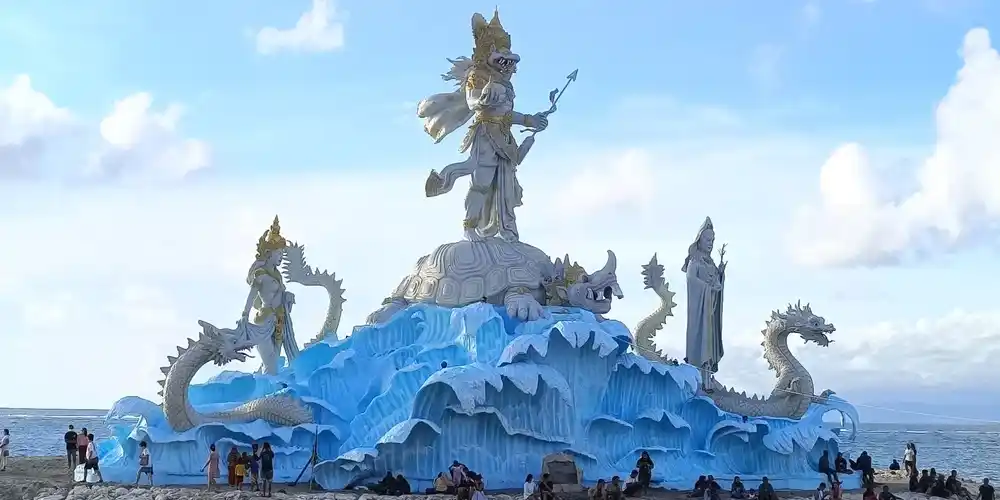 Statue at German Beach (Pantai Jerman) in Bali, featuring a large Balinese Hindu sculpture surrounded by dragon figures and ocean views.