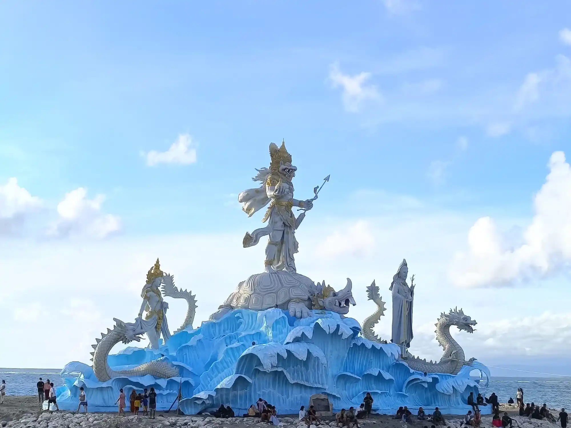 Statue at German Beach (Pantai Jerman) in Bali, featuring a large Balinese Hindu sculpture surrounded by dragon figures and ocean views.