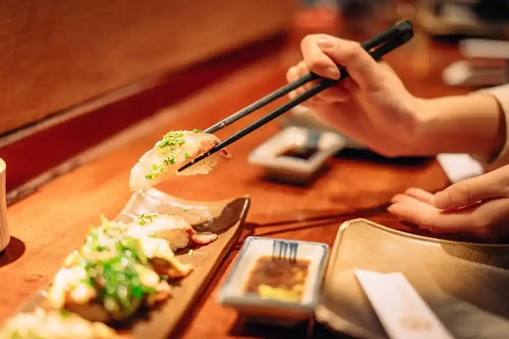 Traditional Japanese sushi served on a wooden table, with chopsticks lifting a piece of sushi.