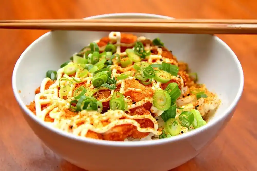 Japanese rice bowl topped with crispy chicken, mayonnaise, spring onions and chilli seasoning.