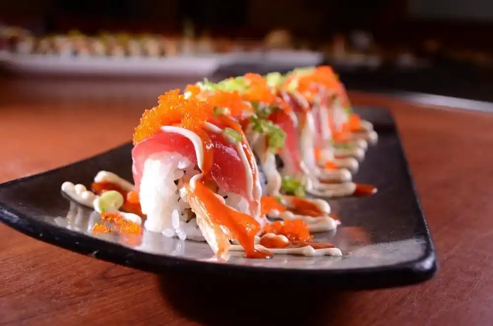 Japanese sushi rolls topped with salmon, fish roe, spring onions and spicy sauce.