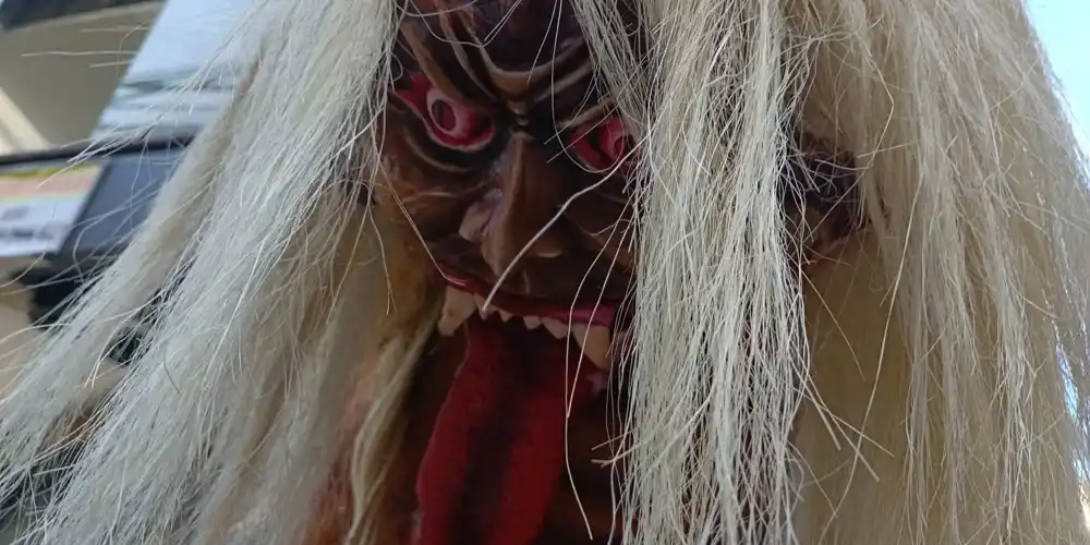Ogoh-ogoh sculpture in Kuta, Bali, depicting a fierce mythical figure with red eyes, sharp teeth, a long red tongue and long white hair.