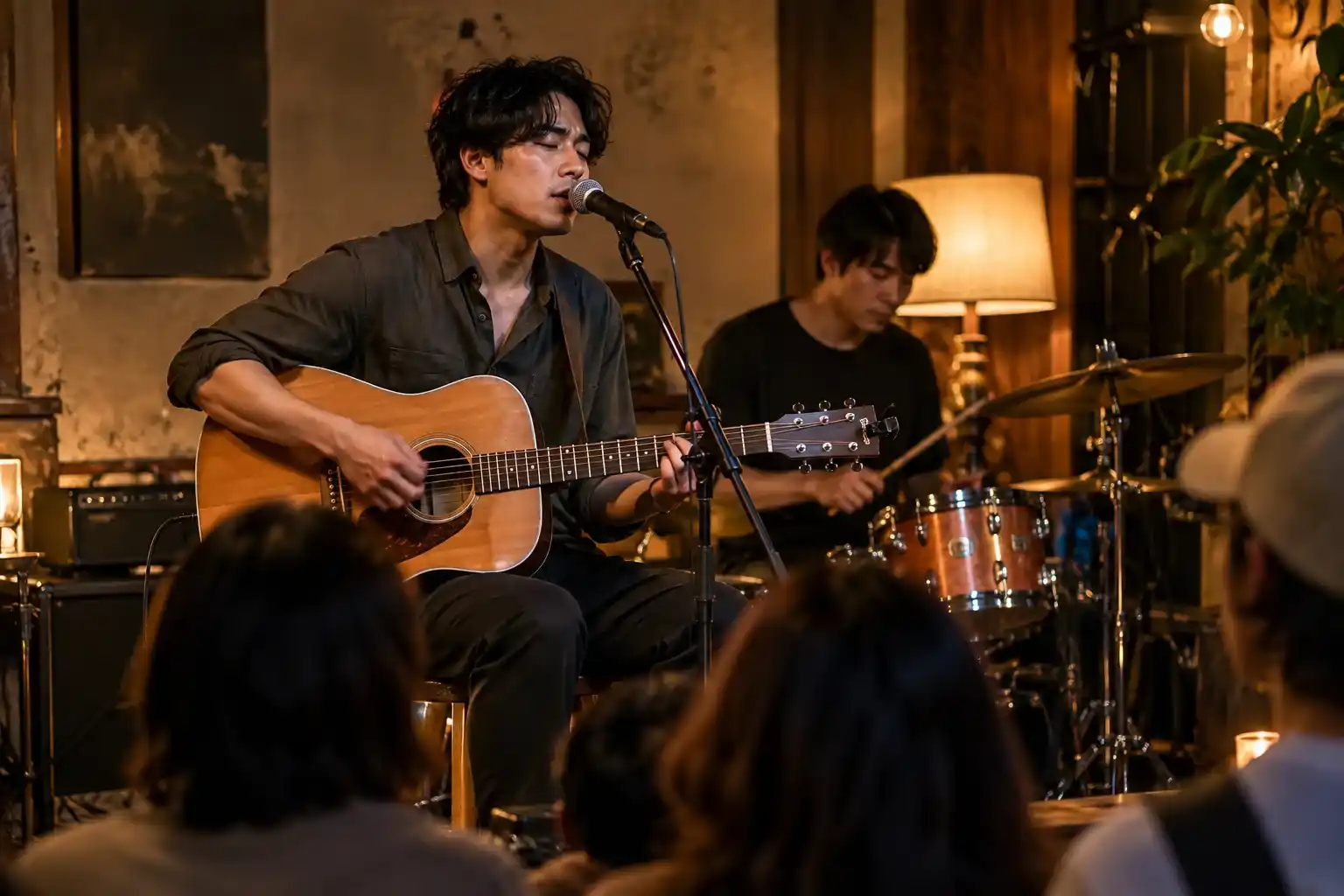 Gitaris Korea Selatan bernyanyi di depan mikrofon saat tampil bersama drummer di tempat musik yang intim.