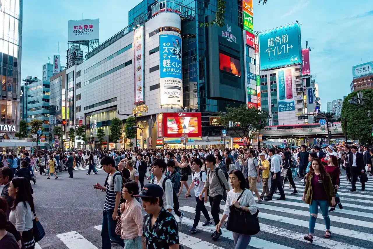 Tokyo’s Shibuya Crossing filled with pedestrians, surrounded by busy streets, shops and illuminated advertising signs.