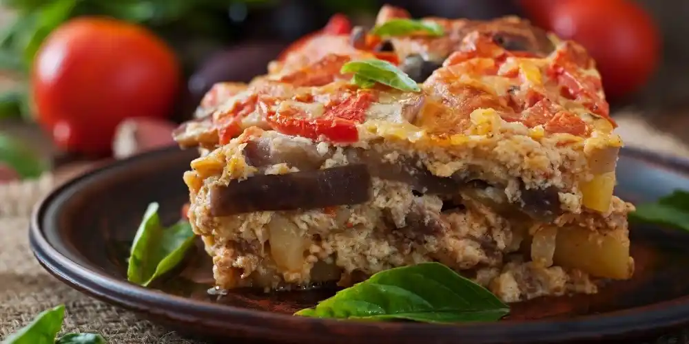 Traditional Greek moussaka with layers of aubergine, meat and béchamel served on a plate.