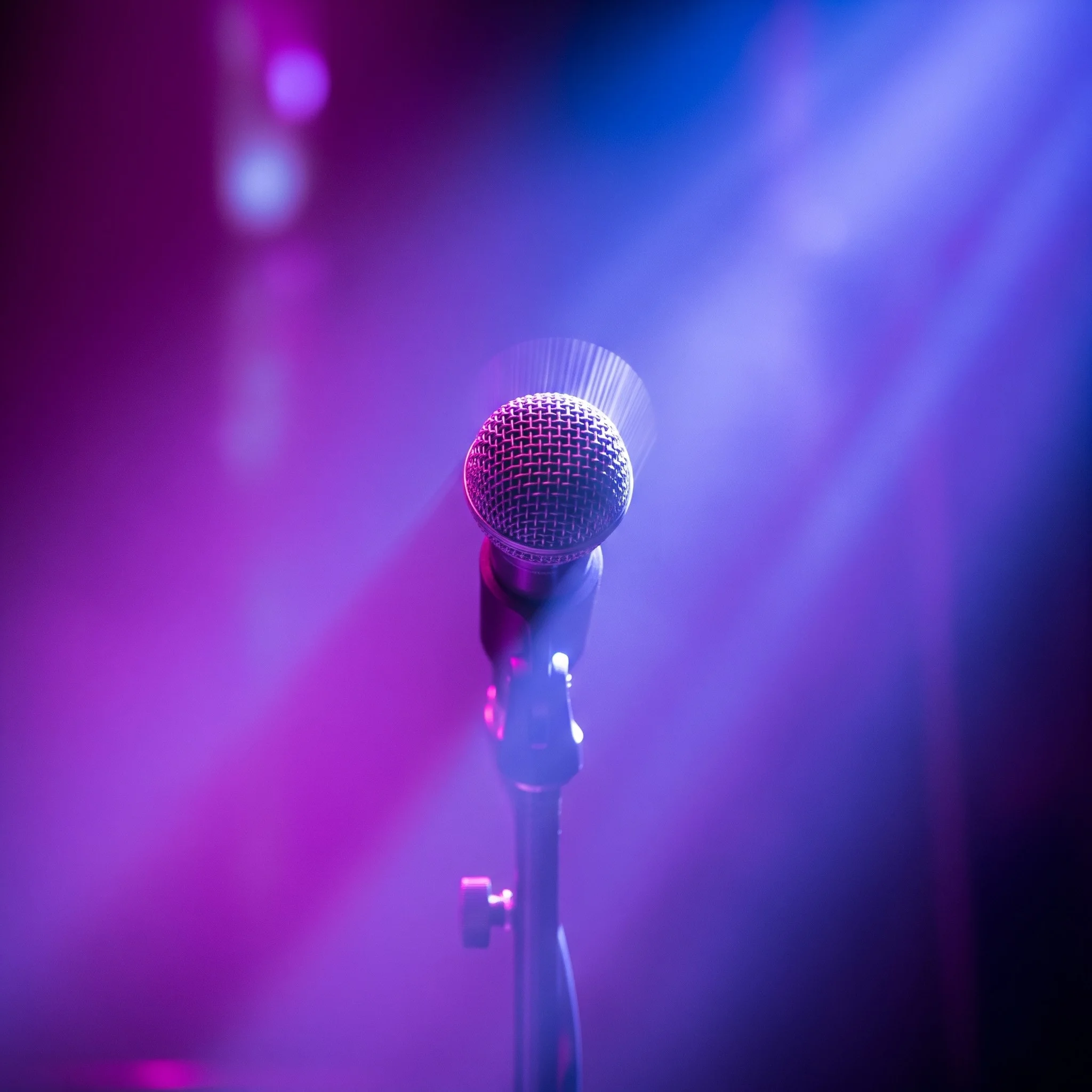 A microphone stand on a purple-lit stage.