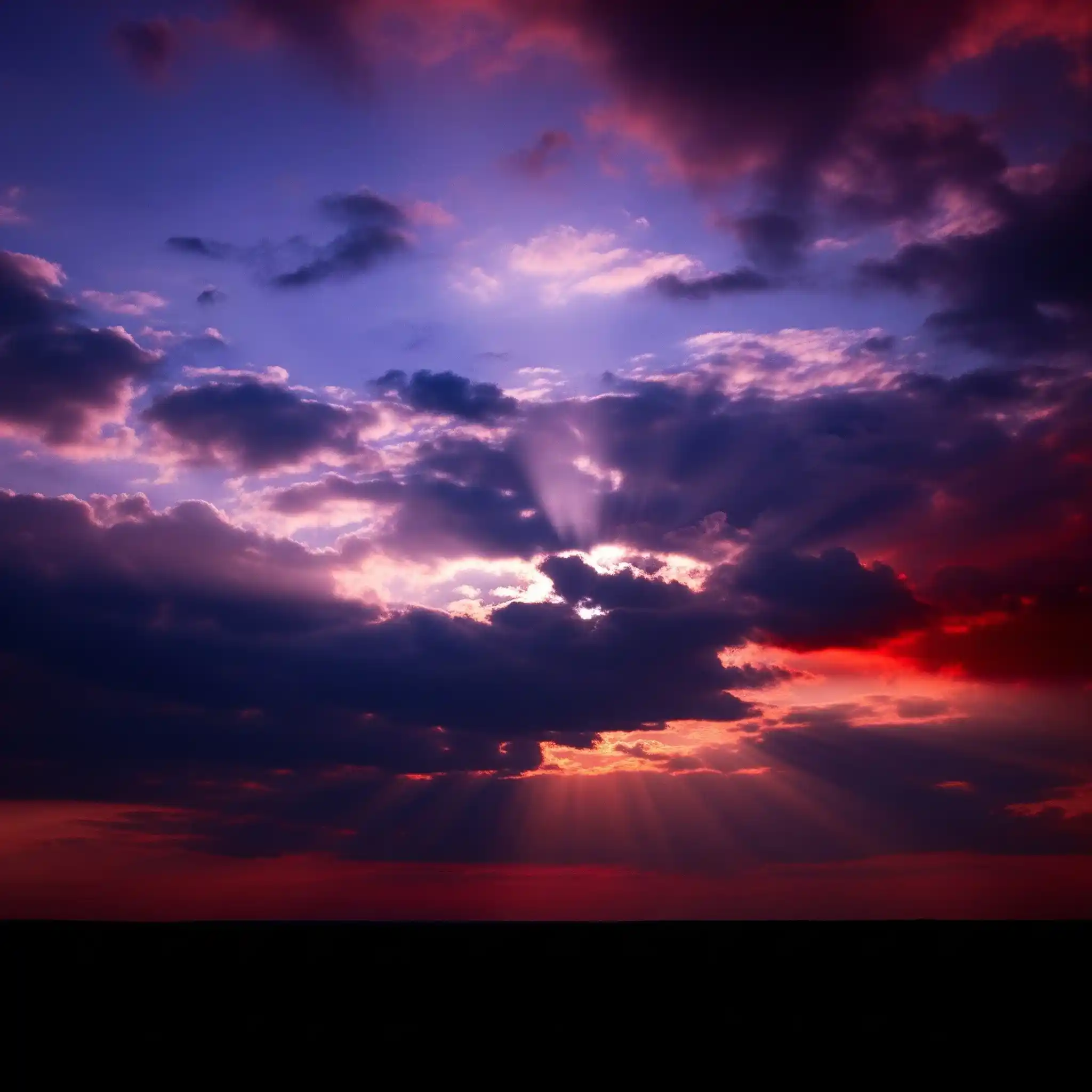 A dramatic sky with swirling purple, blue, and red clouds, and rays of light breaking through.