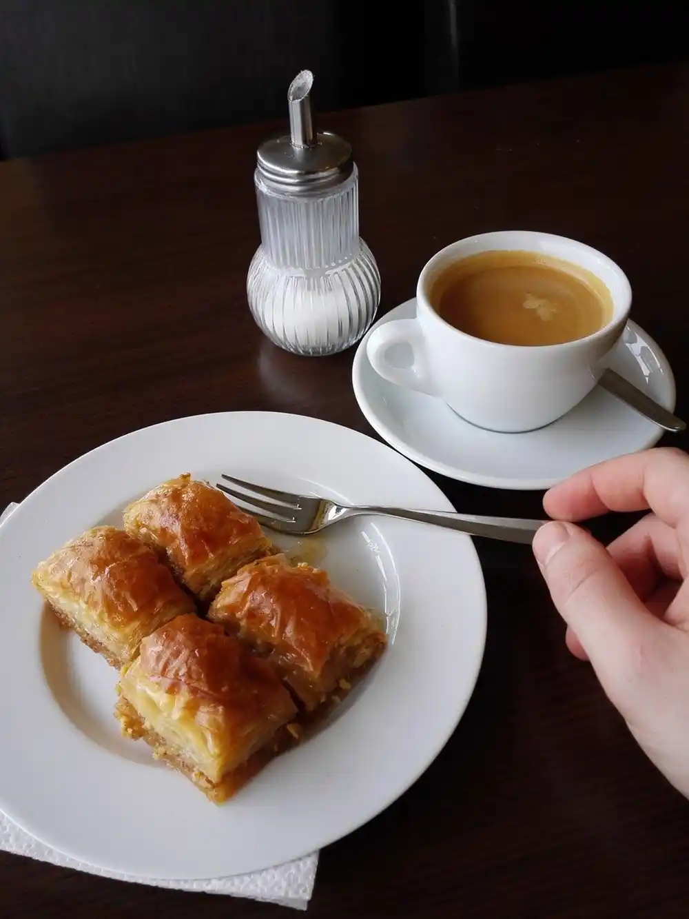 Greek coffee served with Baklava dessert on a plate in a café setting.