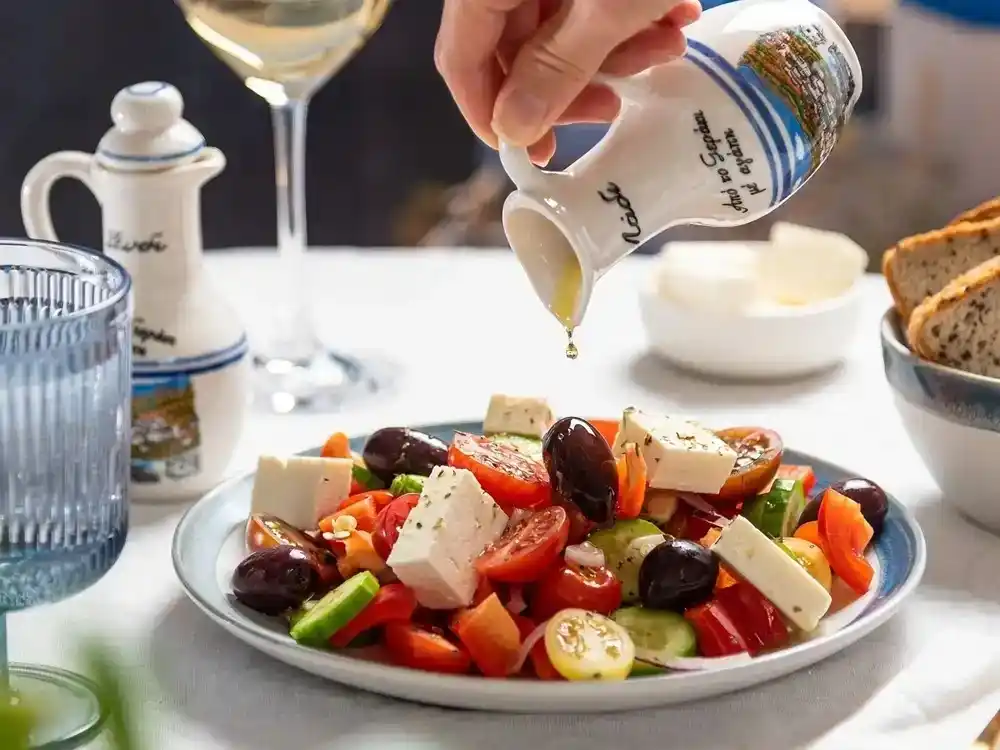 Greek salad with Feta cheese, olives, tomatoes and cucumber drizzled with olive oil.