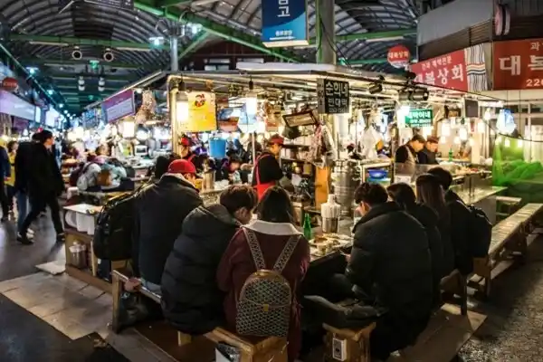 Street food stalls and diners inside Gwangjang Market in Seoul.
