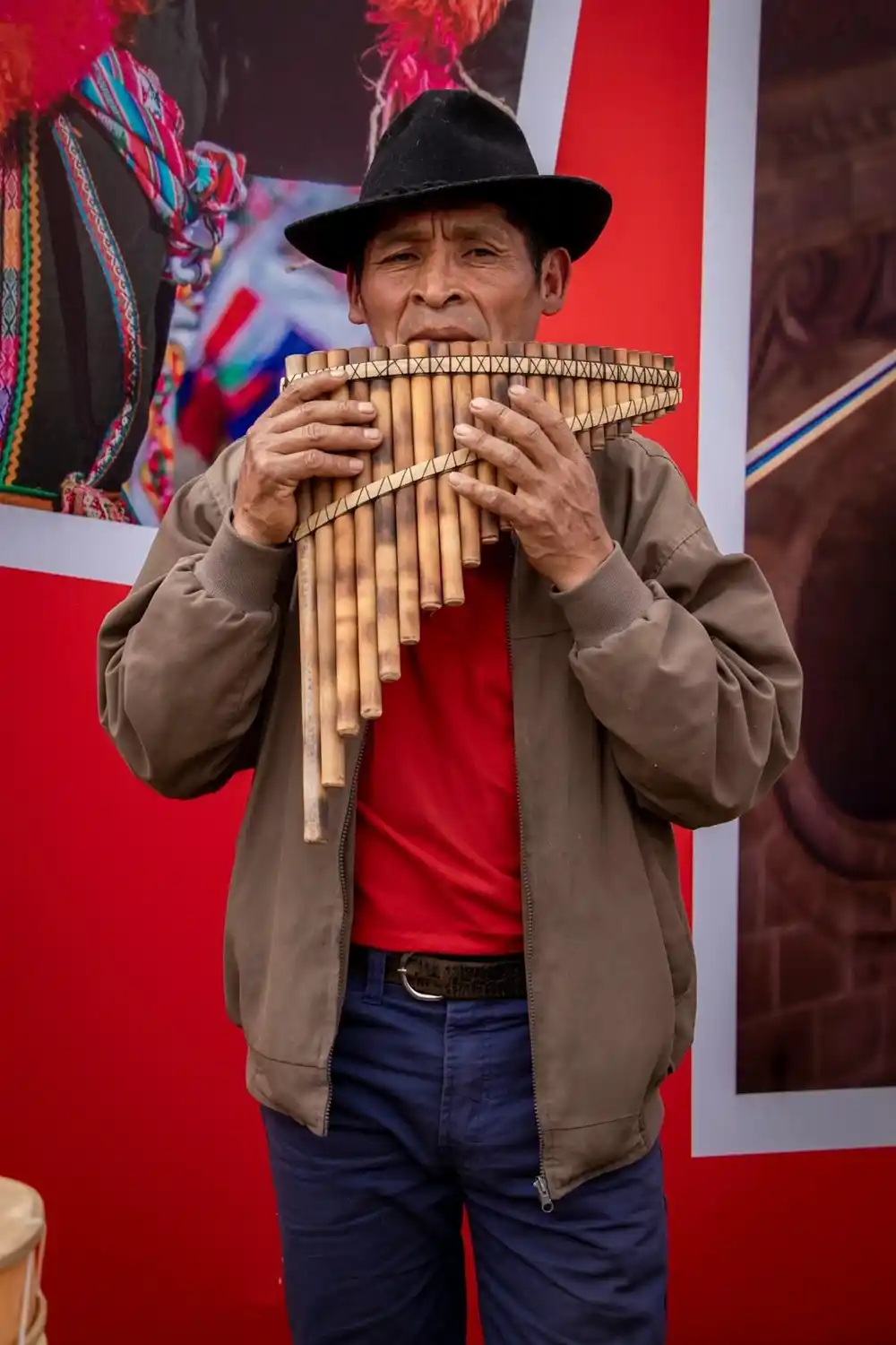 Man playing traditional Andean pan flutes in a vibrant street setting in Peru.
