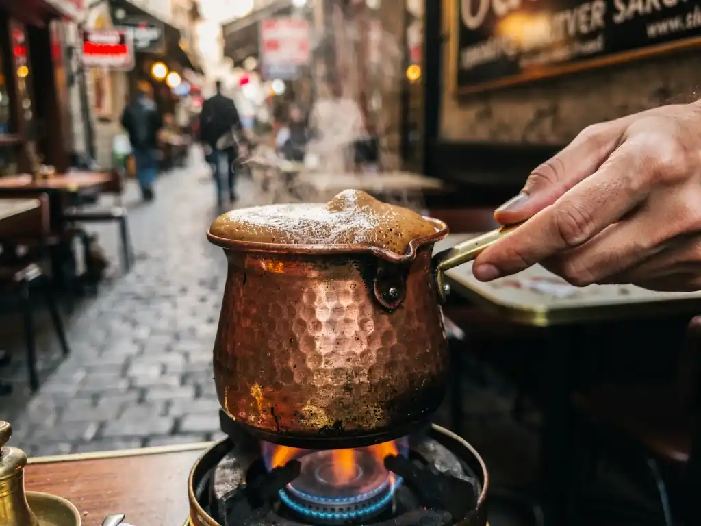 Turkish coffee being prepared in a copper cezve over an open flame in Istanbul.