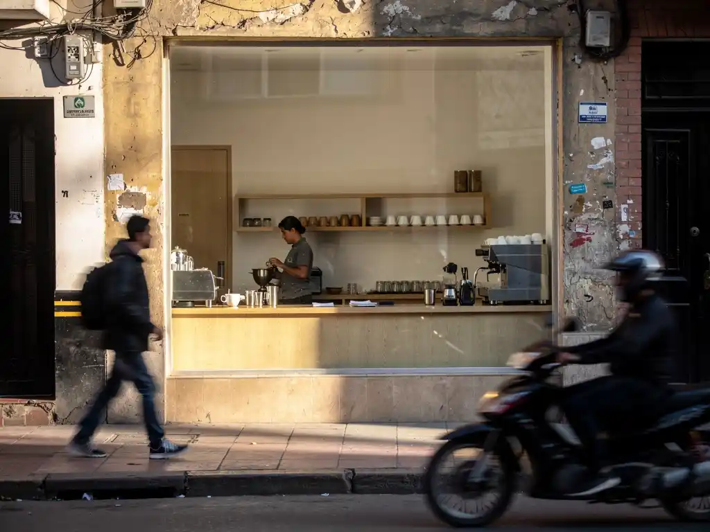 Street view of a Bogotá café with a barista visible inside.