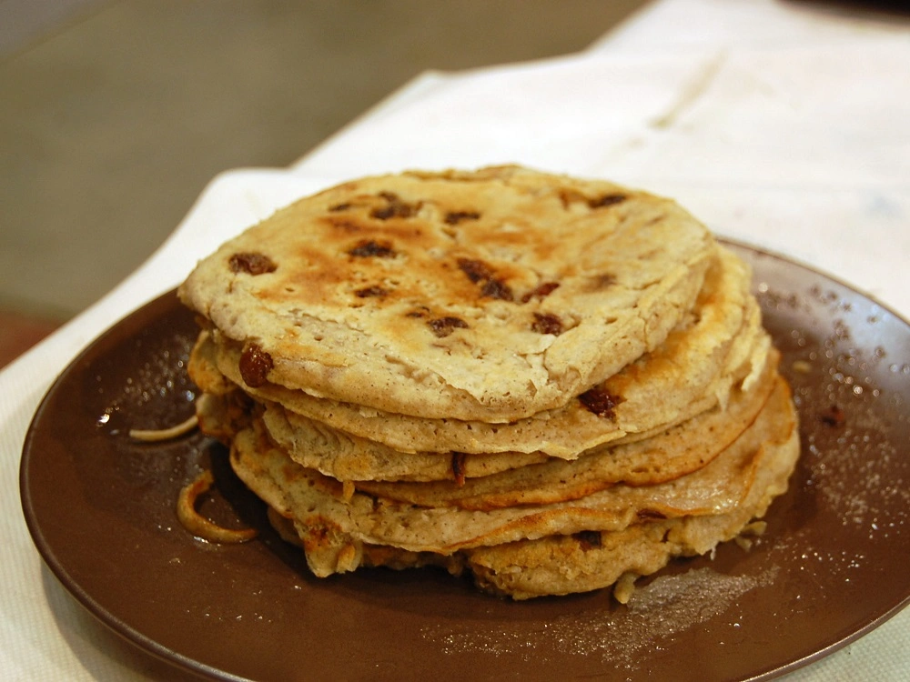 Boûkètes, traditional Liège buckwheat pancakes with raisins, stacked on a plate.