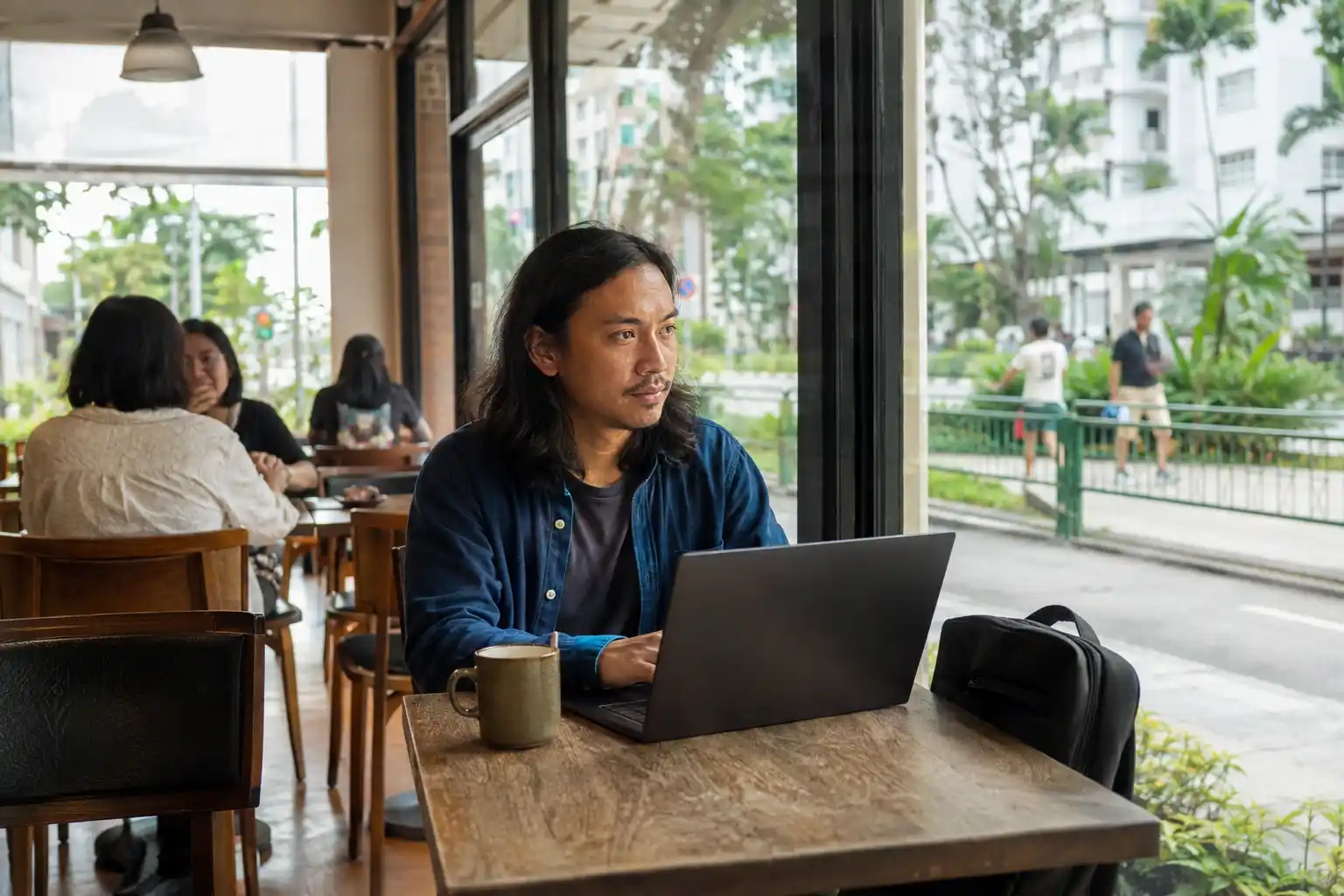 Pria digital nomad bekerja dengan laptop di kafe biasa di Singapura.