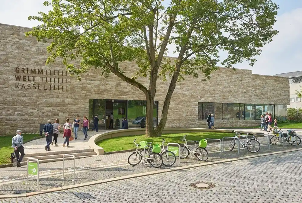 Exterior of GRIMMWELT Kassel museum with visitors and bicycles in Kassel Germany.
