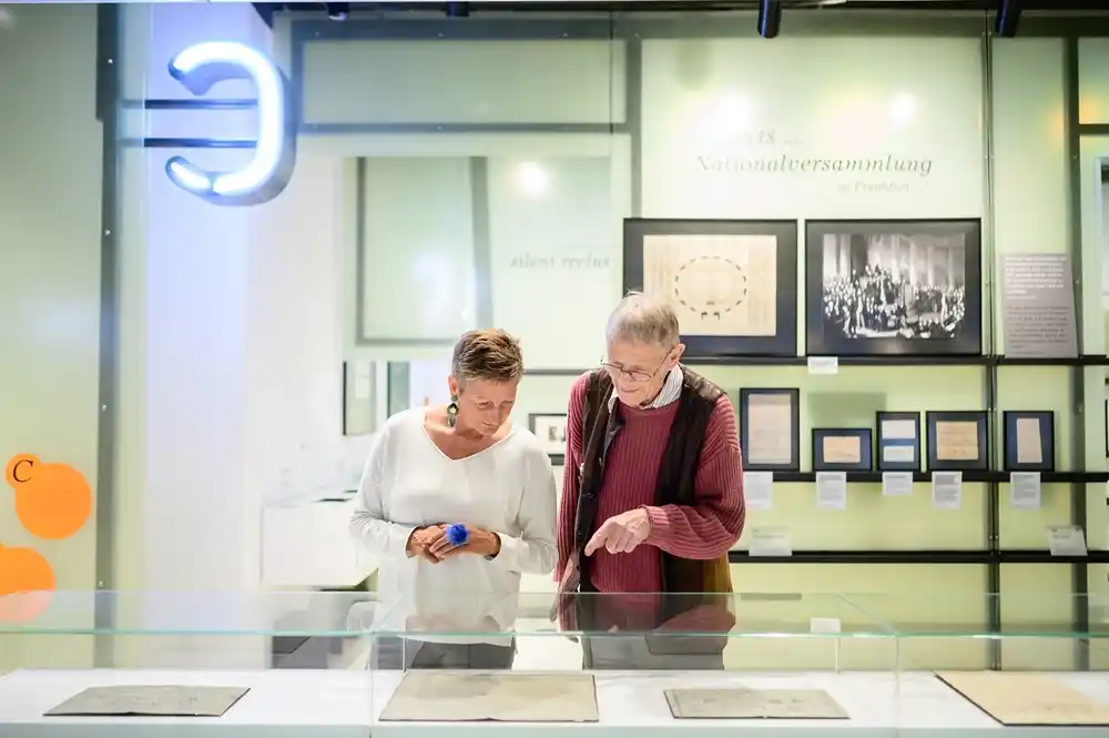 Visitors viewing Grimm brothers manuscripts and exhibits at GRIMMWELT Kassel museum Germany