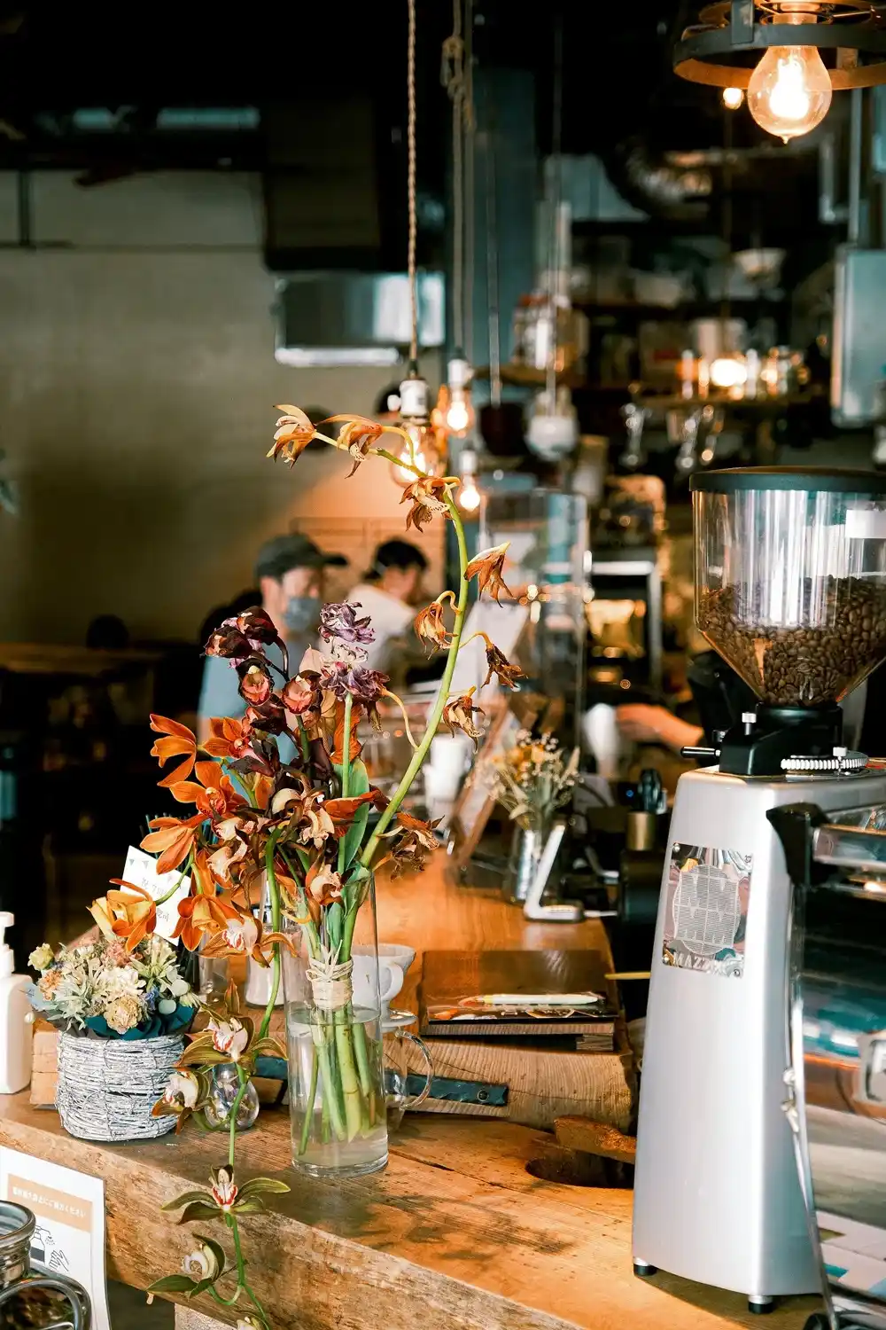 Coffee grinder, beans and flowers arranged on the counter of a Kyoto café.