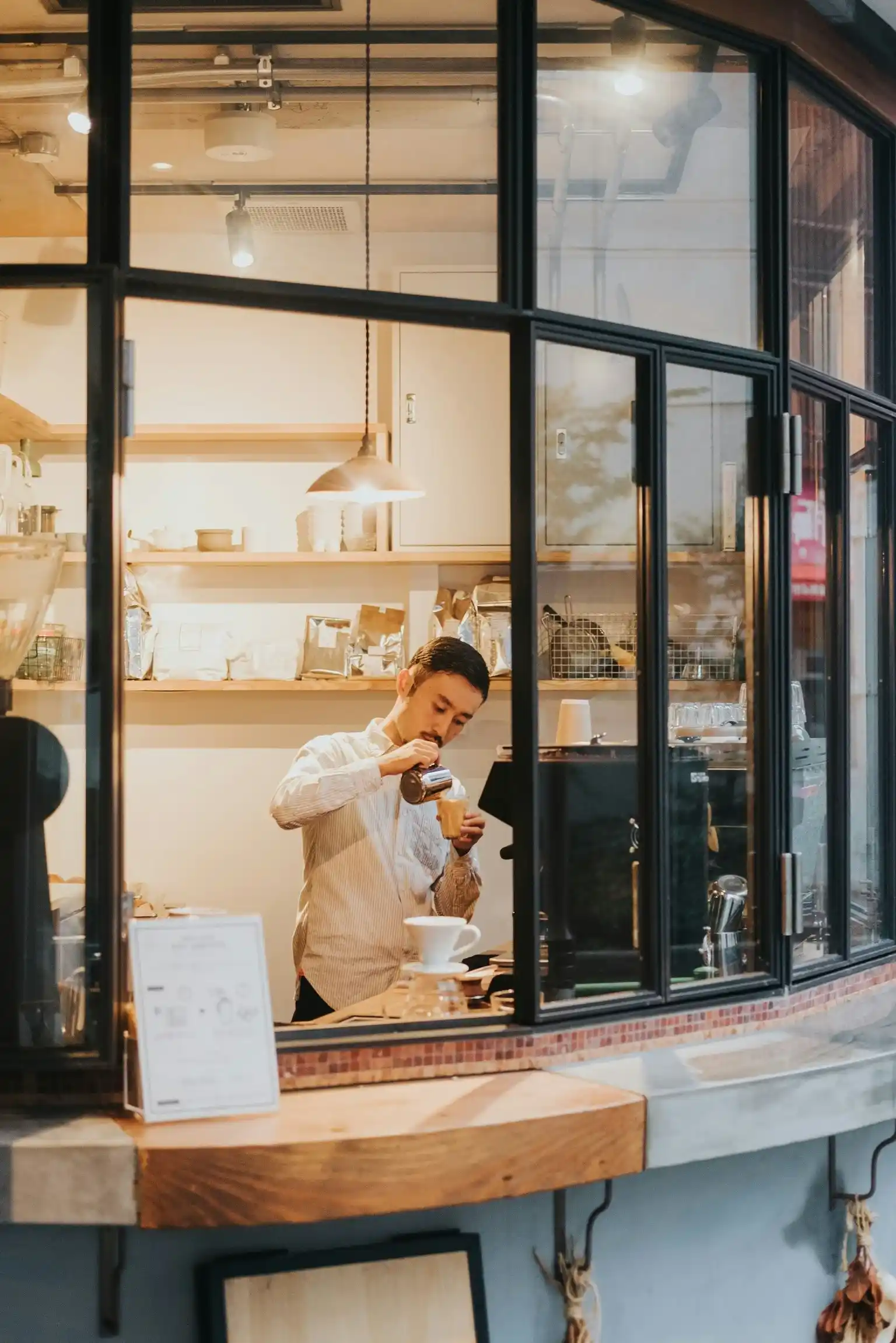 Tokyo barista carefully pouring coffee into a cup behind the counter of a modern café.