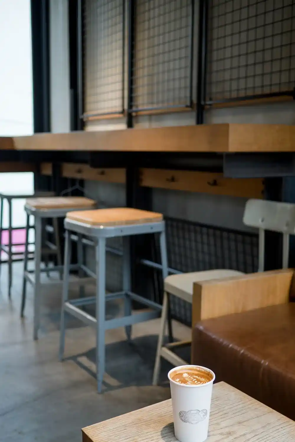 Latte on a wooden table inside a modern Tokyo coffee shop with stools and counter seating.