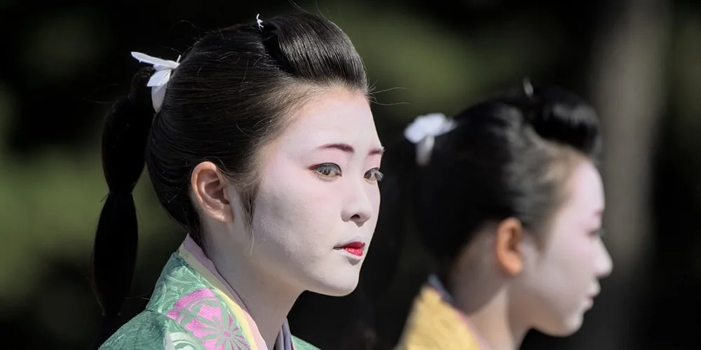 Geisha in traditional kimono and white makeup at a cultural event in Kyoto in Japan.